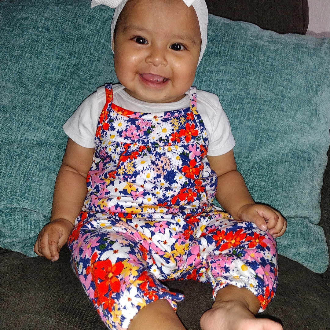 Dianette is registered to the contest to win money with this photo: accessories, baby, clothing, couch, cushion, dress, face, formalwear, furniture, happy, hat, head, homedecor, pants, person, photography, portrait, shorts, sitting, smile