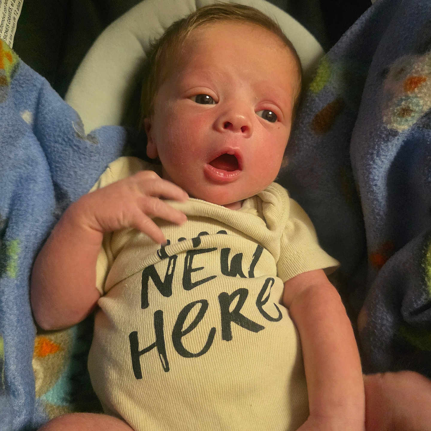 Kaden joined the competition — help win amazing prizes! newborn, baby, infant, onesie, clothing, blanket, blue_blanket, yellow_onesie, expression, face, hand, lying_down, indoors, cozy, cute, small_hands, new_here_text, child, person, wrapped