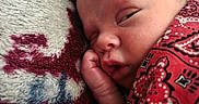 Kaden is registered to the contest to win money with this photo: newborn, baby, infant, sleeping, face, portrait, close_up, blanket, swaddled, textile, patterned, red, cozy, indoors, resting, fist, cheek, peaceful, head, child