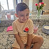Oakley is registered to the contest to win money with this photo: child, boy, smile, kitchen, countertop, flowers, vase, window, daylight, home, cup, plate, granite, furniture, indoor, person, casual_clothing, shorts, tshirt, happy