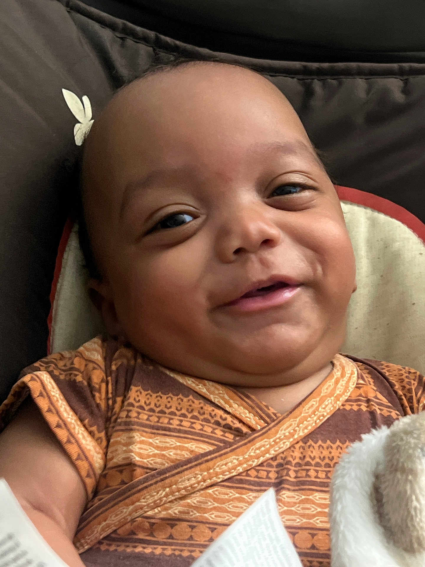 Kameran is registered to the contest to win money with this photo: baby, smile, face, child, infant, clothing, patterned_clothes, cushion, blanket, closeup, happy, portrait, skin, head, person, indoors, comfort, babywear, young_child, expression
