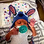 baby, newborn, knitted_hat, pacifier, sleeping, infant, striped_blanket, hospital, medical_tube, hand, cute, colorful, heart_pattern, white_clothing, bed, soft_lighting, indoors, peaceful, tiny, portrait