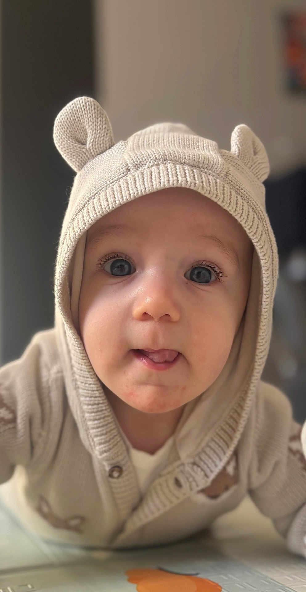 Lyam a rejoint le concours — aidez-le/la à gagner de superbes lots ! baby, infant, child, knit_hood, bear_ears, cardigan, tongue_out, big_eyes, eyelashes, close_up, portrait, indoor, soft_lighting, blurred_background, adorable, rosy_cheeks, cozy, neutral_colors, front_view, facial_expression