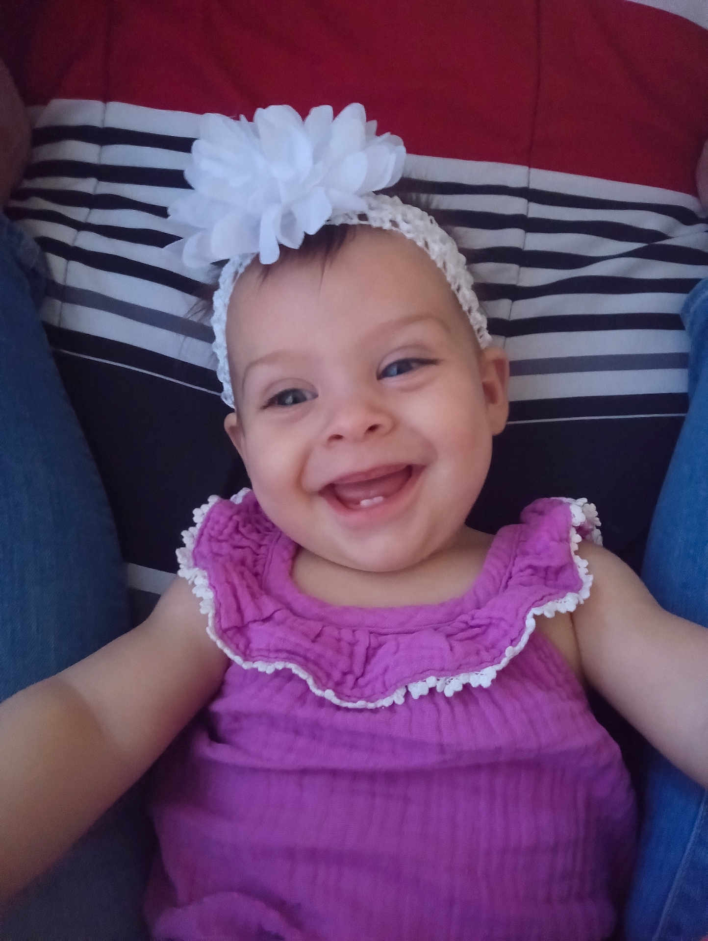 Nevaeh is registered to the contest to win money with this photo: baby, child, smile, headband, flower, purple_dress, happy, face, person, cushion, striped_background, legs, seated, indoors, cute, infant, joy, apparel, portrait, closeup