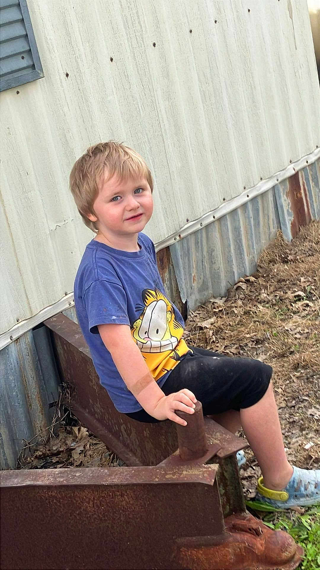 Lex joined the competition — help win amazing prizes! child, boy, outdoor, rust, metal, building, tshirt, shorts, grass, leaves, blue_eyes, blonde_hair, sitting, hand, footwear, smile, casual_clothing, nature, dirt, daylight
