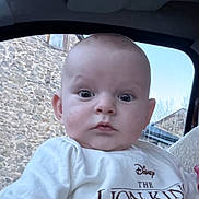 Elie participe au concours pour gagner de l'argent avec cette photo : baby, child, infant, face, person, clothing, tshirt, cartoon_character, lion_king, car_interior, window, stone_wall, sky, cute, expression, eyes, head, sitting, blanket, indoors