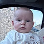 baby, child, infant, face, person, clothing, tshirt, cartoon_character, lion_king, car_interior, window, stone_wall, sky, cute, expression, eyes, head, sitting, blanket, indoors