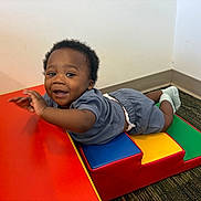 Amir joined the competition — help win amazing prizes! baby, carpet, child, clothing, colorful, corner, face, floor, happy, head, indoor, padded_ramp, person, play, playground_equipment, shorts, smiling, socks, toddler, wall