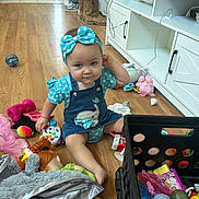 Dakota joined the competition — help win amazing prizes! baby, child, toddler, sitting, portrait, smiling, bow, headband, polka_dot, denim_overalls, dress, toy, playroom, doll, stuffed_animal, ball, wooden_floor, indoors, furniture, colorful