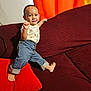 toddler, child, smiling, indoor, couch, pillow, red_pillow, maroon_couch, orange_curtains, barefoot, jeans, shirt, happy, posing, balance, home, furniture, person, portrait, cute