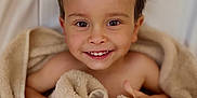 Lyam participe au concours pour gagner de l'argent avec cette photo : beige_towel, big_eyes, blanket, brown_hair, child, closeup, fabric, hands, happy, indoor, natural_light, portrait, skin, smile, teeth, thumbs_up, toddler, towel, wet_hair, wooden_floor