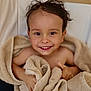 beige_towel, big_eyes, blanket, brown_hair, child, closeup, fabric, hands, happy, indoor, natural_light, portrait, skin, smile, teeth, thumbs_up, toddler, towel, wet_hair, wooden_floor