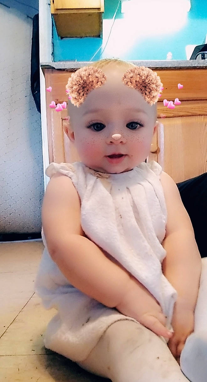 Julie is registered to the contest to win money with this photo: baby, baby_toddler_clothing, day_dress, doll, dress, embellishment, peach, person, pink, sitting, toddler, toy