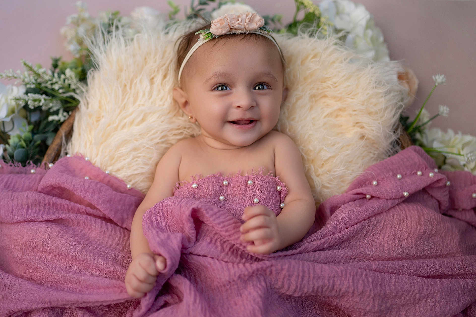 Sridha joined the competition — help win amazing prizes! baby, smiling, blanket, pink, headband, flower, fluffy, pillow, cute, portrait, child, happy, infant, closeup, indoors, soft_texture, decor, person, wrapped, skin