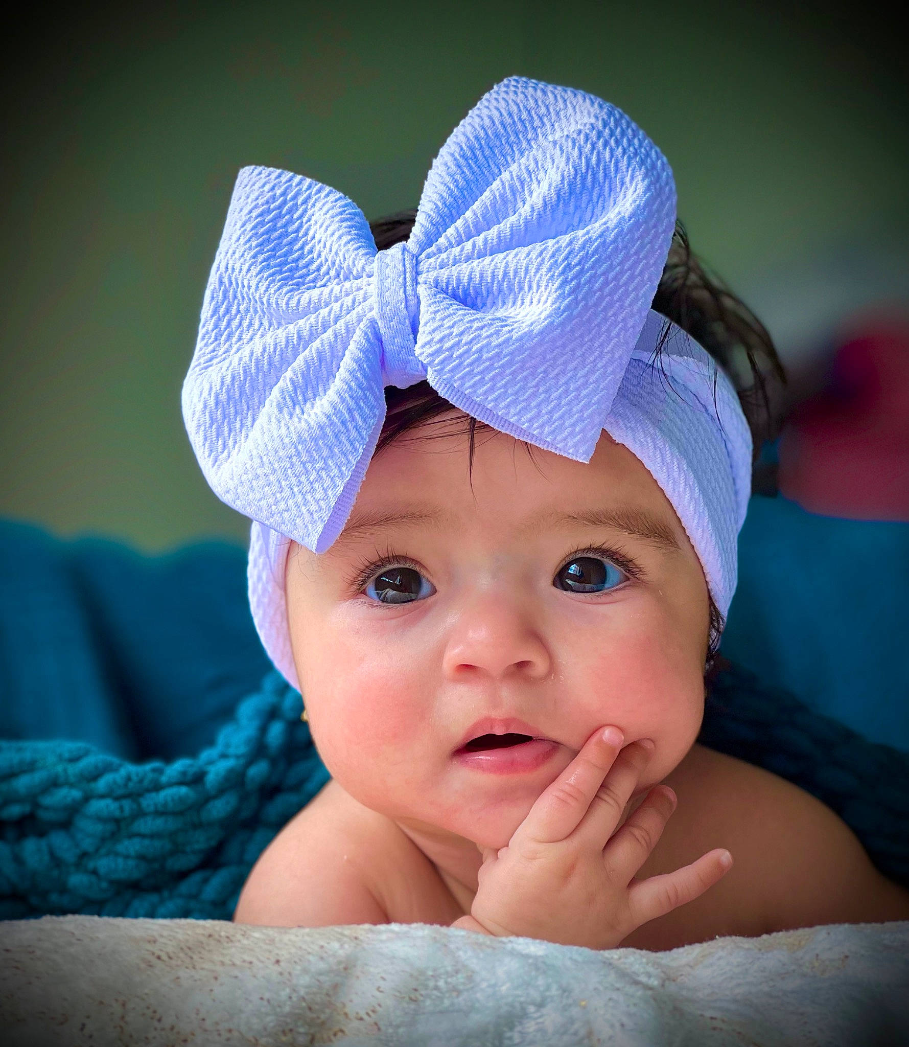 Naomi is registered to the contest to win money with this photo: aqua, baby, baby_toddler_clothing, cap, close_up, comfort, electric_blue, fashion_accessory, finger, fun, gesture, hair_accessory, happy, hat, headgear, headwear, magenta, person, purple, thumb