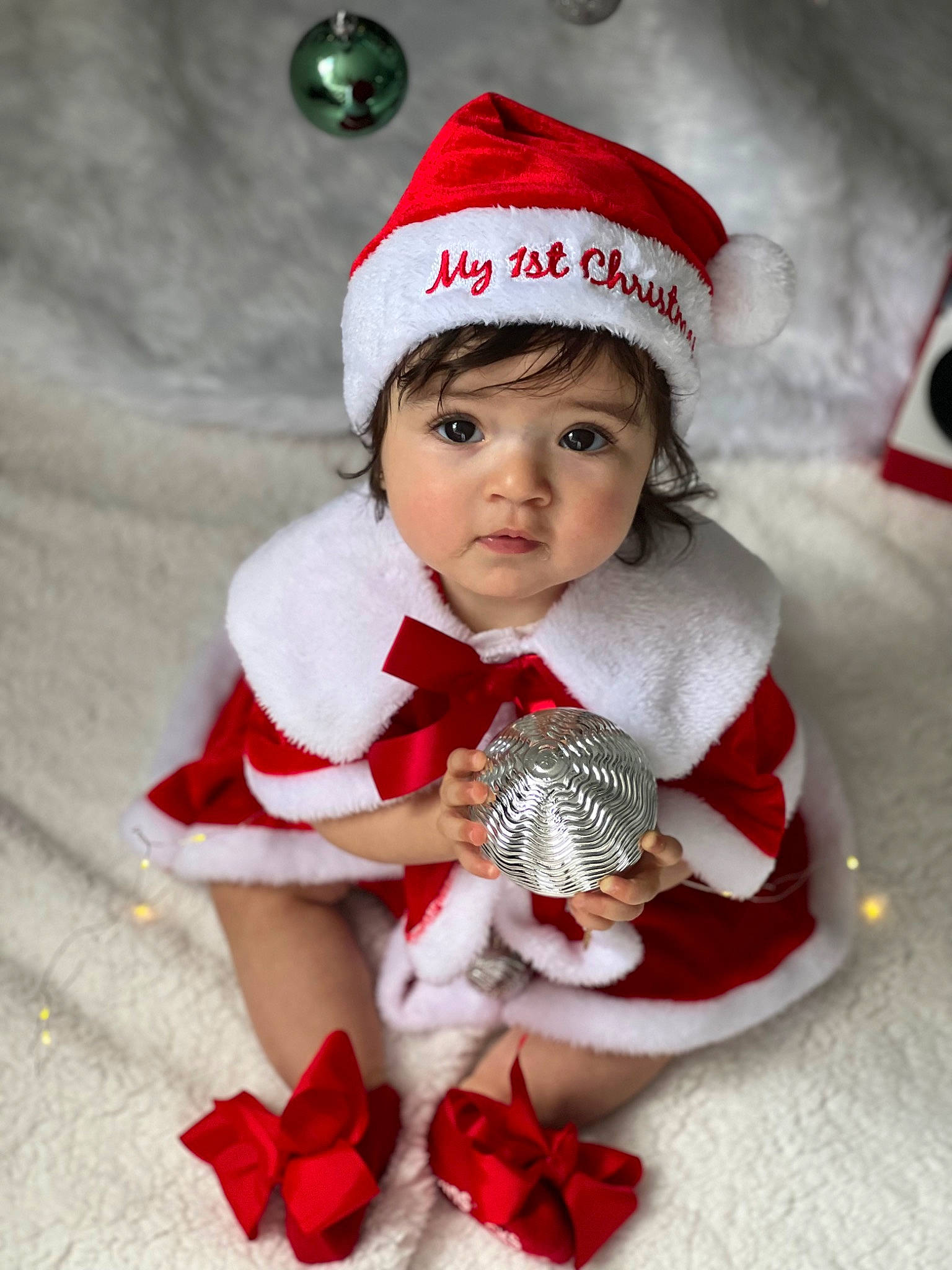 Naomi joined the competition — help win amazing prizes! baby_toddler_clothing, cap, child, christmas, christmas_ornament, costume_hat, event, fictional_character, happy, hat, headwear, holiday, holiday_ornament, ornament, pattern, person, red, santa_claus, sleeve, sock