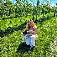 Loki joined the competition — help win amazing prizes! woman, dog, border_collie, smiling, outdoors, orchard, apple_trees, grass, sunlight, nature, garden, fruit, blue_sky, portrait, pet, hugging, crouching, summer, rural, photography