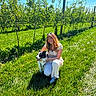 woman, dog, border_collie, smiling, outdoors, orchard, apple_trees, grass, sunlight, nature, garden, fruit, blue_sky, portrait, pet, hugging, crouching, summer, rural, photography