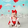 baby, child, smiling, sitting, red_bow, heart_pattern, white_clothing, red_dress, tights, floor, studio, background, clouds, balloons, heart_balloons, cute, portrait, happy, indoor, infant
