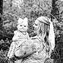 Loretta is registered to the contest to win money with this photo: baby, child, woman, tattoo, bow, dress, floral_pattern, outdoor, nature, trees, smile, holding, portrait, black_and_white, happy, person, cute, family, mother, infant