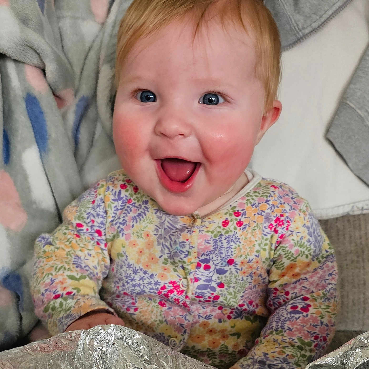 Eira joined the competition — help win amazing prizes! baby, blanket, blue_eyes, child, clothing, cozy, cute, fabric, face, floral_clothing, foil, happy, head, indoor, infant, person, portrait, rosy_cheeks, sitting, smiling