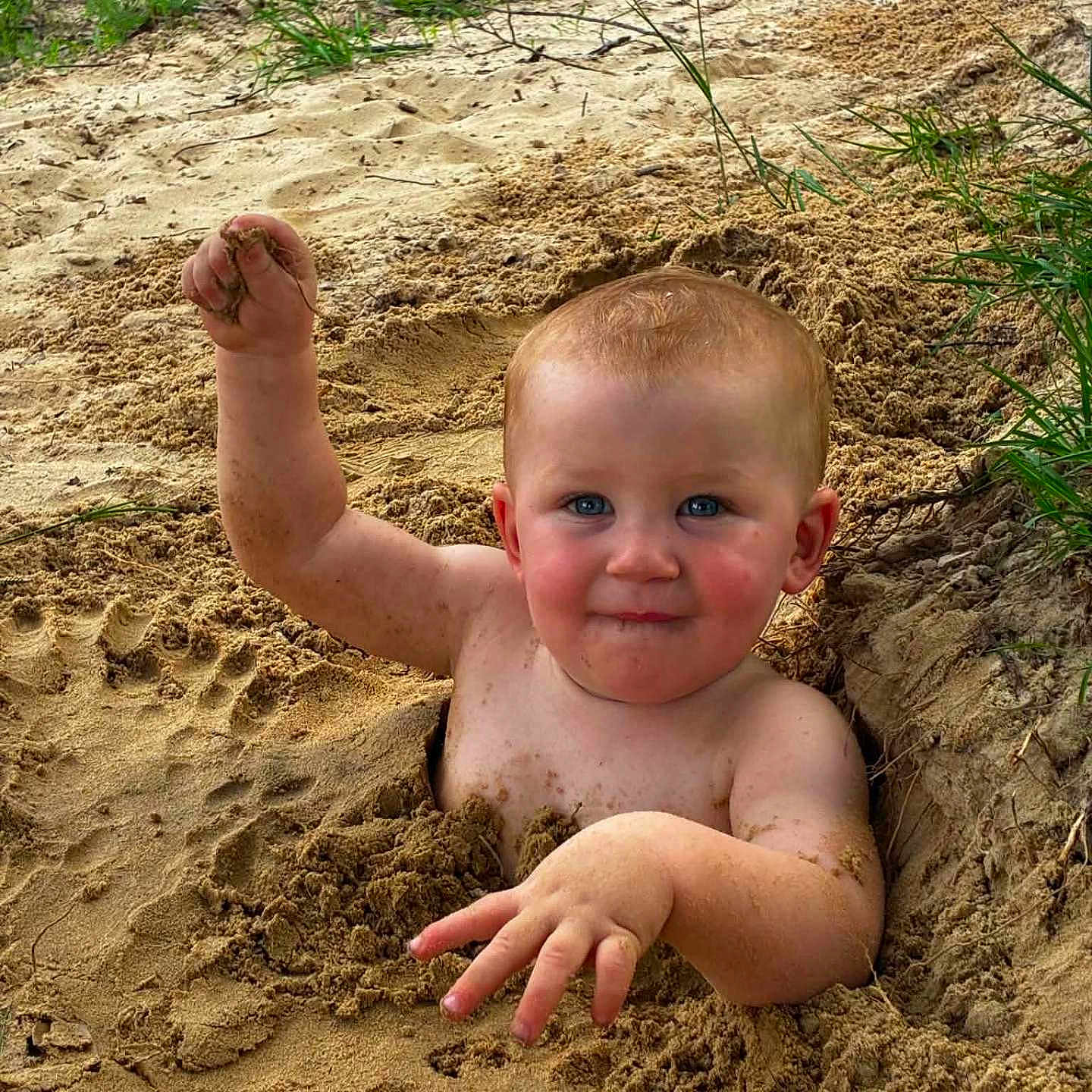 Kayden is registered to the contest to win money with this photo: child, toddler, sand, outdoor, play, dirt, happy, smiling, blue_eyes, bare_chest, nature, grass, sunlight, fun, messy, summer, cute, face, hand, baby