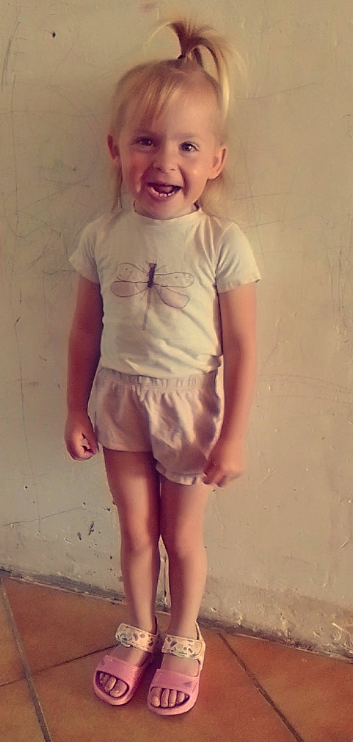 Céléna a rejoint le concours — aidez-le/la à gagner de superbes lots ! baby_toddler_clothing, barefoot, blond, face, happy, human_leg, joy, knee, pattern, peach, person, pink, shorts, skin, sleeve, smile, summer, t_shirt, thigh, toddler