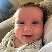 Robyn joined the competition — help win amazing prizes! baby, infant, face, eyes, clothing, onesie, hair, skin, indoor, couch, person, portrait, cute, expression, closeup, smile, child, young, newborn, soft_lighting