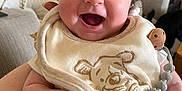 Robyn is registered to the contest to win money with this photo: baby, smiling, indoor, bib, person, face, happy, infant, clothing, hand, living_room, furniture, parrot, birdcage, animal, cute, joyful, portrait, closeup, skin