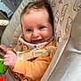 Robyn is registered to the contest to win money with this photo: baby, smiling, infant, baby_chair, toy, green_toy, orange_sweater, bib, face, hand, cushion, bear_pattern, indoor, cute, child, young_child, happy, portrait, seat, comfort