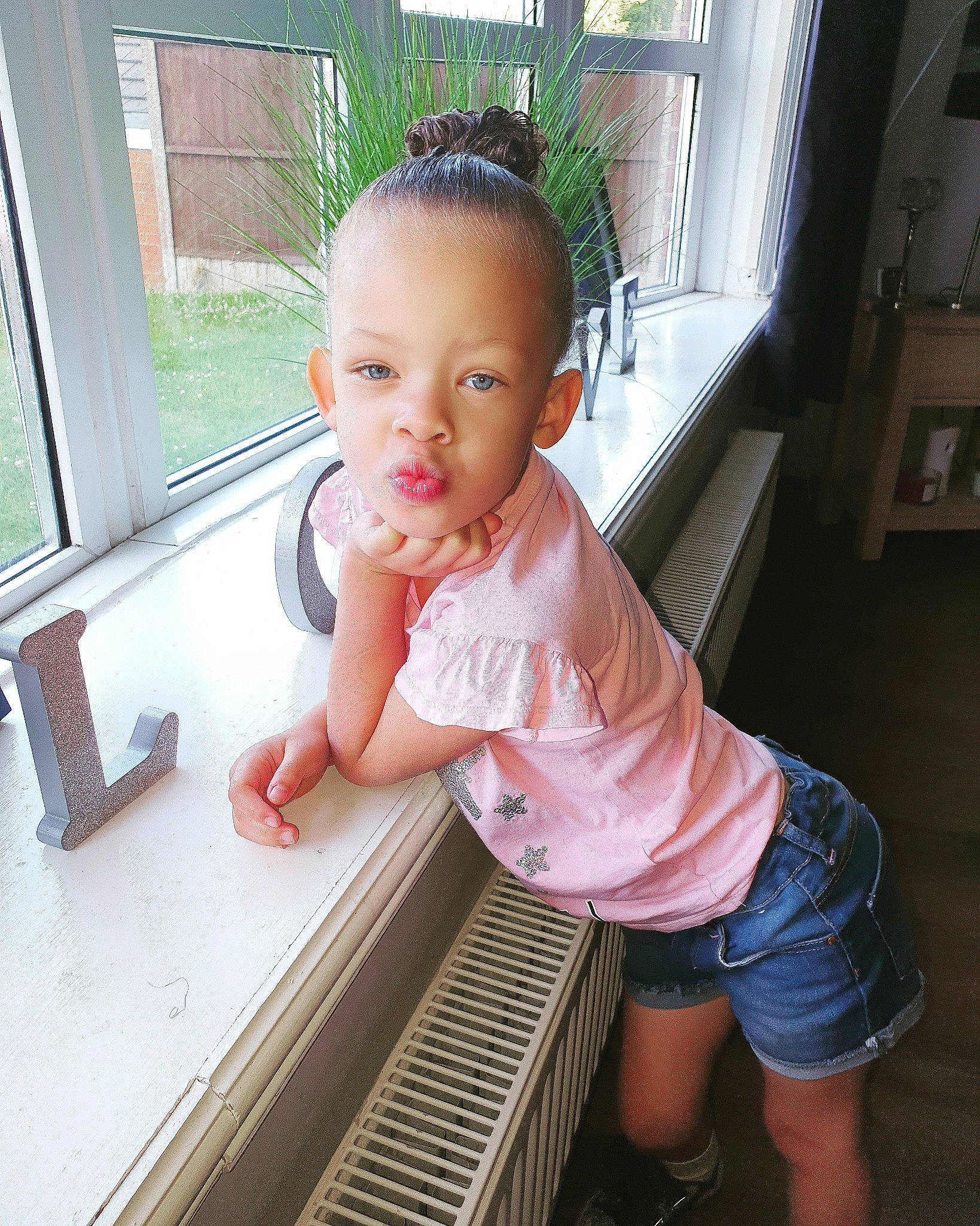 Esmee is registered to the contest to win money with this photo: baby, beauty, cheek, child, electronic_device, eye, face, head, leg, nose, person, pink, skin, smile, standing, summer, toddler, vacation, window