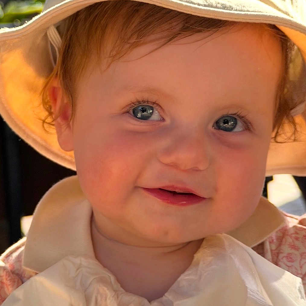Alera is registered to the contest to win money with this photo: toddler, child, face, hat, smile, sunlight, bib, portrait, outdoor, baby, cute, happy, headwear, skin, young, person, clothing, closeup, expression, daylight