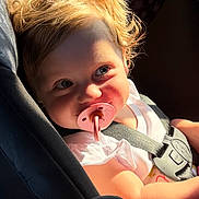 Alera Capri is registered to the contest to win money with this photo: baby, blonde_hair, car_seat, child, close_up, eyes, face, greenery, infant, outdoor, pacifier, photography, pink_clothing, portrait, road_trip, safety_harness, seated, smiling, sunlight, vehicle