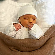 Antoine a rejoint le concours — aidez-le/la à gagner de superbes lots ! newborn, baby, sleeping, white_hat, white_knitwear, blanket, brown_blanket, cozy, infant, cute, peaceful, resting, indoors, soft_texture, portrait, child, warm, hands, face, sleep