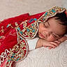 Noor is registered to the contest to win money with this photo: baby, sleeping, red_shawl, gold_embroidery, soft_cushion, peaceful, infant, portrait, close_up, face, hand, cozy, resting, cute, newborn, indoors, decorative_fabric, warm, relaxed, child