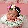 baby, sleeping, flower_headband, pink_background, knitted_blanket, peaceful, infant, resting, cute, portrait, soft_lighting, closeup, child, newborn, hands, face, cozy, warm_colors, adorable, peaceful_sleep
