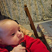 Wesley a rejoint le concours — aidez-le/la à gagner de superbes lots ! baby, child, red_clothing, tattoo, hand, face, curtain, chair, table, indoor, person, closeup, pattern, wood, furniture, holding, skin, portrait, infant, candid