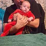 Wesley a rejoint le concours — aidez-le/la à gagner de superbes lots ! baby, adult, holding, red_clothing, indoor, table, towel, person, portrait, hands, face, sitting, wallpaper, floral_pattern, casual_clothing, skin, table_cover, home, family, comfort