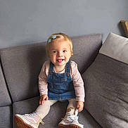 Ruby participe au concours pour gagner de l'argent avec cette photo : toddler, child, smiling, tongue_out, denim_overall, pink_shirt, tights, sneakers, sitting, couch, gray_couch, hair_clips, indoor, playful, happy, person, furniture, young_child, blonde_hair, casual_clothing