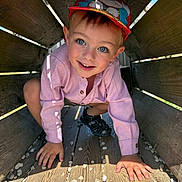 Noevann participe au concours pour gagner de l'argent avec cette photo : blue_eyes, boy, cap, casual_clothing, child, crouching, cute, happy, hat, outdoor, play, playground, portrait, shadow, shoes, smiling, stones, sunlight, wood, wooden_tunnel