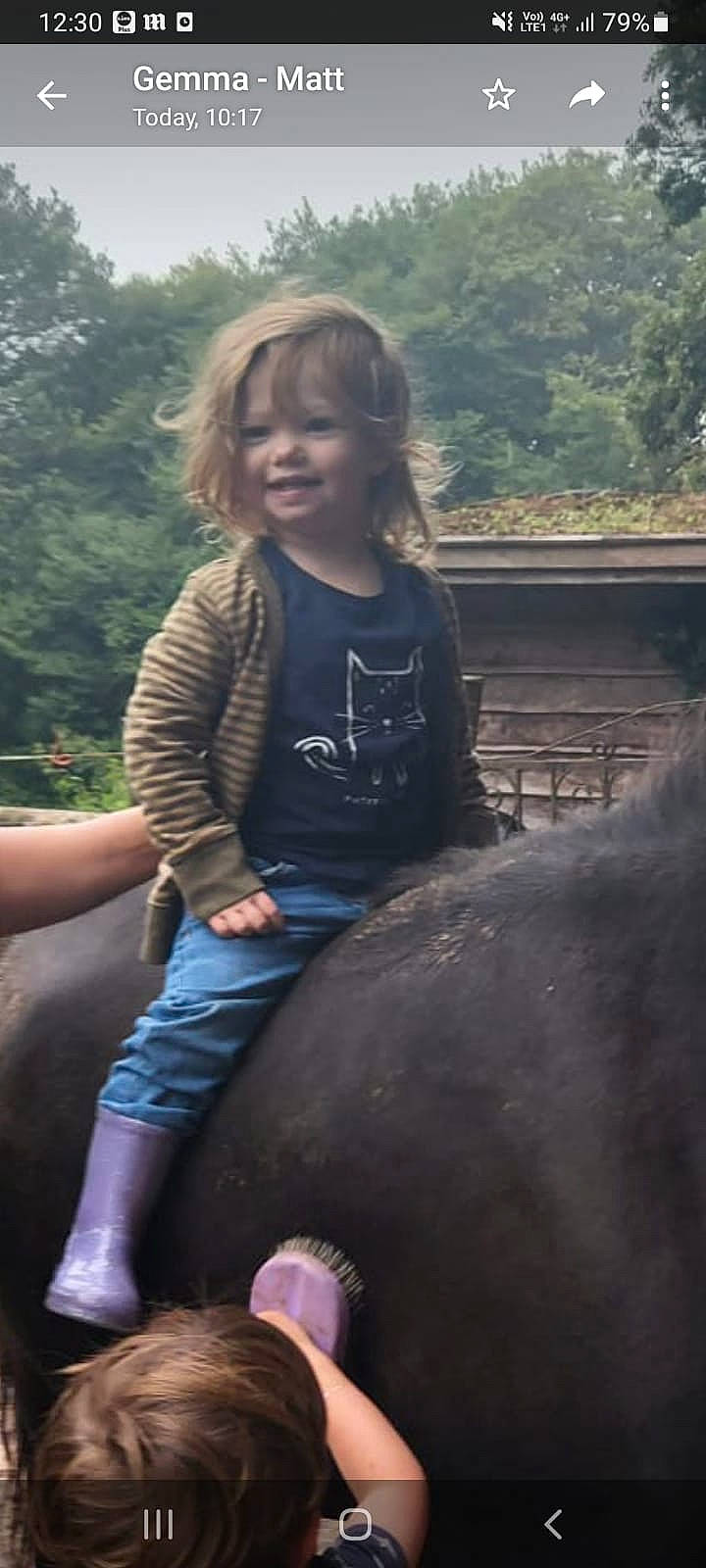 Aila is registered to the contest to win money with this photo: child, cool, eye, fun, grass, happy, joy, landscape, leisure, mammal, organ, pack_animal, person, recreation, sitting, skin, t_shirt, terrestrial_animal, toddler, tree