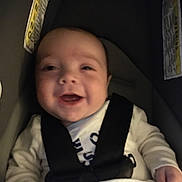 Skylo is registered to the contest to win money with this photo: baby, infant, smiling, car_seat, carseat_strap, buckle, seat, baby_clothes, onesie, closeup, portrait, happy, laughing, indoor, blurry, soft_lighting, hand, head, face, child