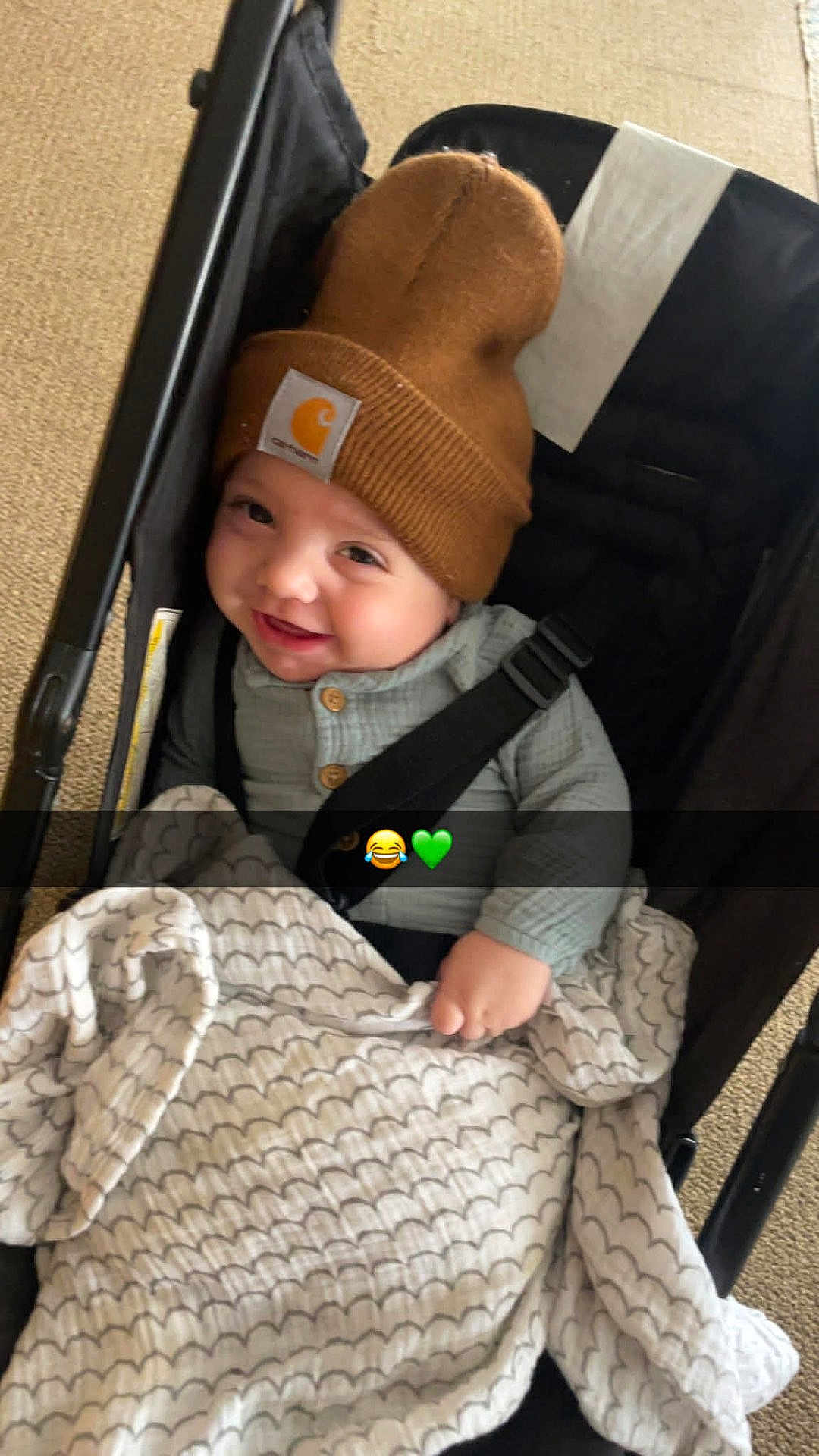 Skylo joined the competition — help win amazing prizes! baby, infant, child, stroller, beanie, hat, smile, blanket, car_seat, seatbelt, happy, cute, indoors, carpet, buttoned_shirt, cheeky_grin, cozy, plush_blanket, emoji_overlay, portrait