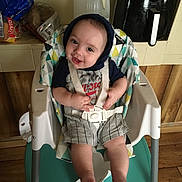 Skylo is registered to the contest to win money with this photo: baby, high_chair, smiling, child, indoors, hoodie, seatbelt, kitchen, bread, water_jug, wood_floor, plastic_chair, person, cute, happy, sitting, infant, face, clothing, appliance