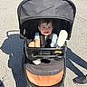 baby, black, blue, canopy, casual, child, clothing, daytime, footwear, happy, outdoor, pavement, person, seat, shadow, shoes, smiling, stroller, sunlight, toddler