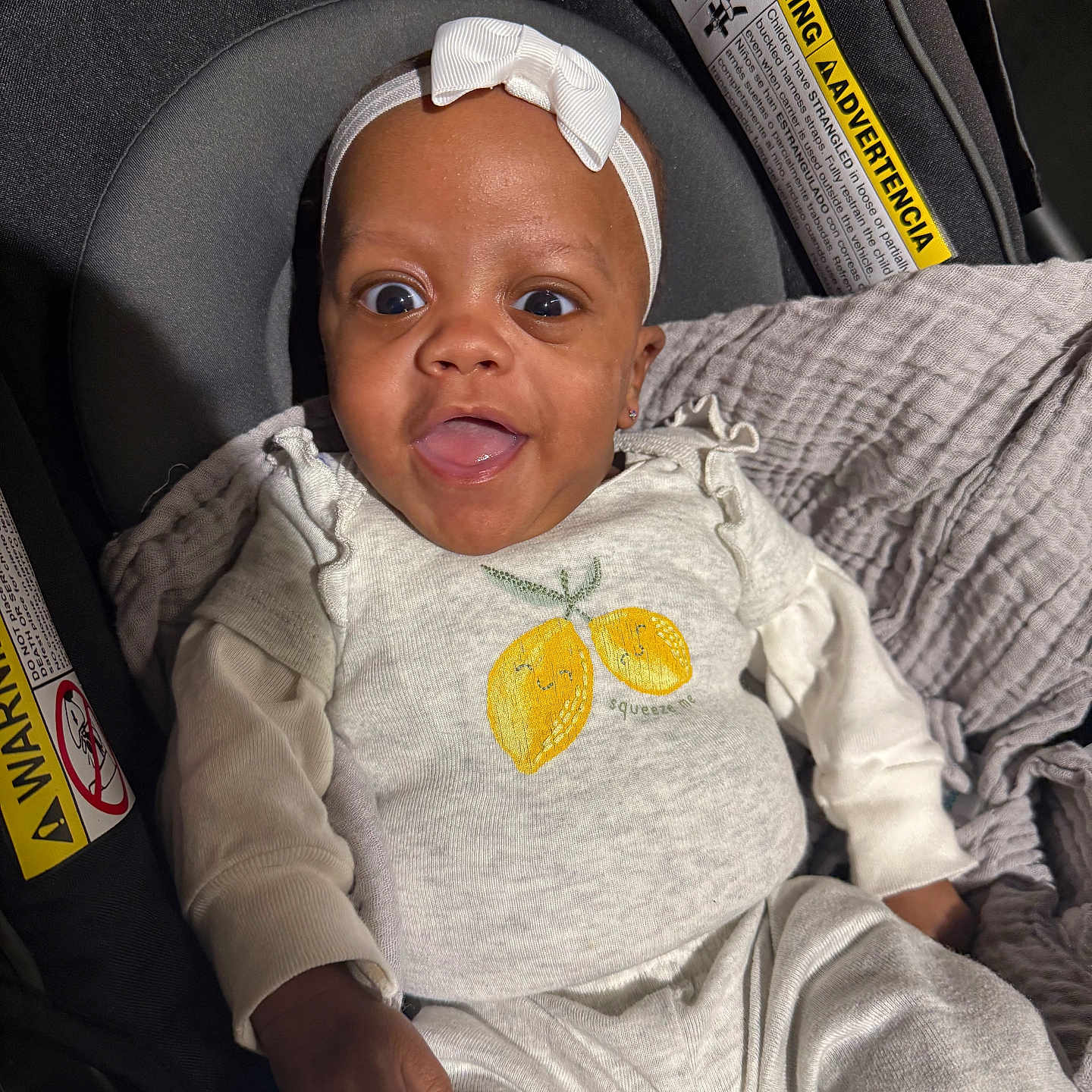 Khayier joined the competition — help win amazing prizes! baby, blanket, car_seat, child, clothing, cute, expression, happy, head, headband, indoor, infant, lemon_graphic, person, portrait, safety_warning, seat, smiling, white_clothing, young_child