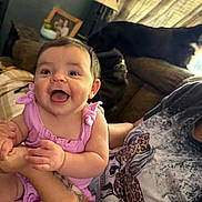 Avery is registered to the contest to win money with this photo: baby, child, smile, happy, pink_clothing, tattoo, arm, person, dog, couch, lamp, flowers, photo_frame, indoor, home, furniture, holding, cute, portrait, living_room