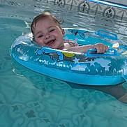 Jordan joined the competition — help win amazing prizes! baby, child, pool, water, inflatable_ring, smiling, happy, tiled_floor, blue, swimming, floating, fun, summer, playful, cute, indoors, person, toddler, wet_hair, splash