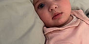 Jordan is registered to the contest to win money with this photo: baby, child, infant, face, pillow, bed, pink_clothing, person, sleepwear, cute, portrait, skin, young, indoors, resting, lying_down, soft, calm, expression, human