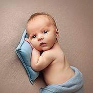 Greyson is registered to the contest to win money with this photo: baby, infant, blue_pillow, blanket, resting, curious_expression, wide_eyes, soft_texture, beige_background, skin, newborn, portrait, lying_down, cute, child, peaceful, tender, wrapped, face, head